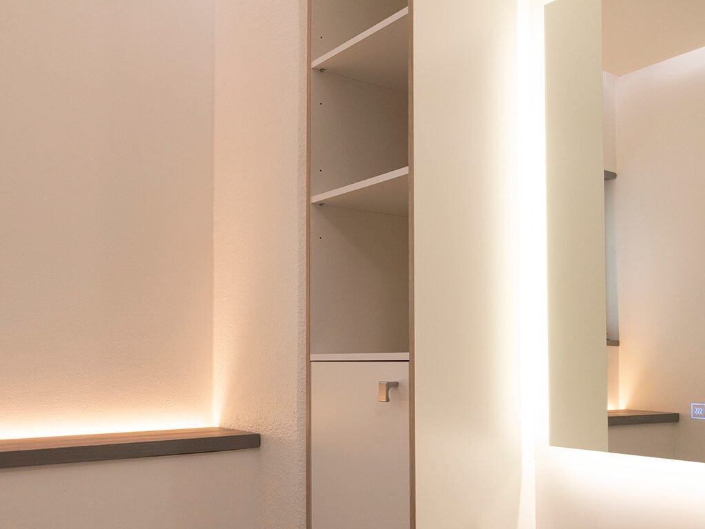 Minimalistinen sisustus, modernit LED-valaistut hyllyt, peilattu seinä, pehmeä valaistus. Neutraalit värit ja selkeät linjat luovat tyylikkään ja tyylikkään tilan.